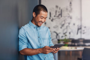 Un homme souriant en regardant sur sa tablette la plateforme axa-mon-epargne-entreprise.com