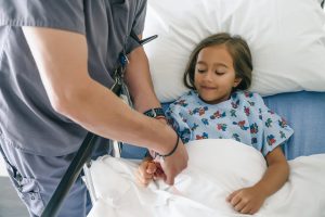 Une petite fille dans un lit d'hôpital avec un médecin qui lui met un bracelet