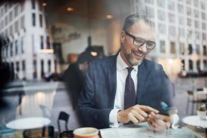 Un homme en costume sur son téléphone regardant l'aide en ligne first web épargne salariale retraite