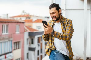 Un homme sur son balcon avec son téléphone dans la main sur l'application AXA épargne salariale