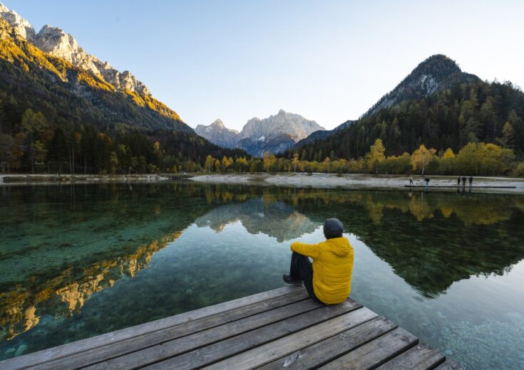 Un homme de dos regardant le lac et les montagnes face à lui - loi industrie verte