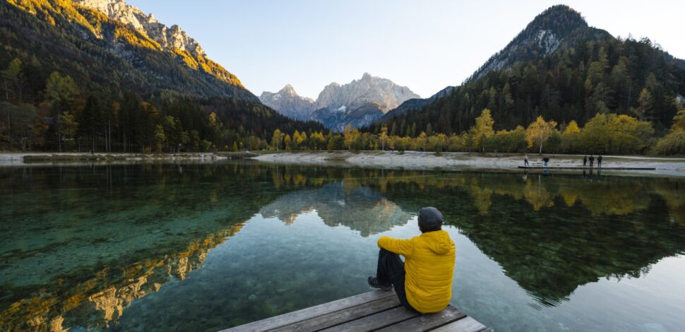 Un homme de dos regardant le lac et les montagnes face à lui - loi industrie verte