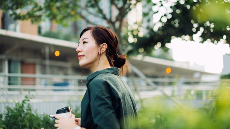 Une femme dehors avec un café à la main - PEE