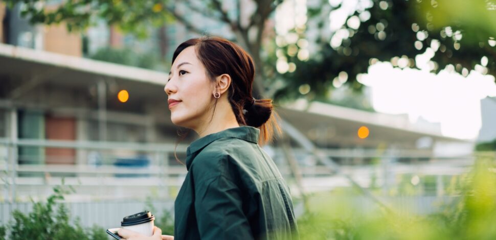 Une femme dehors avec un café à la main - PEE