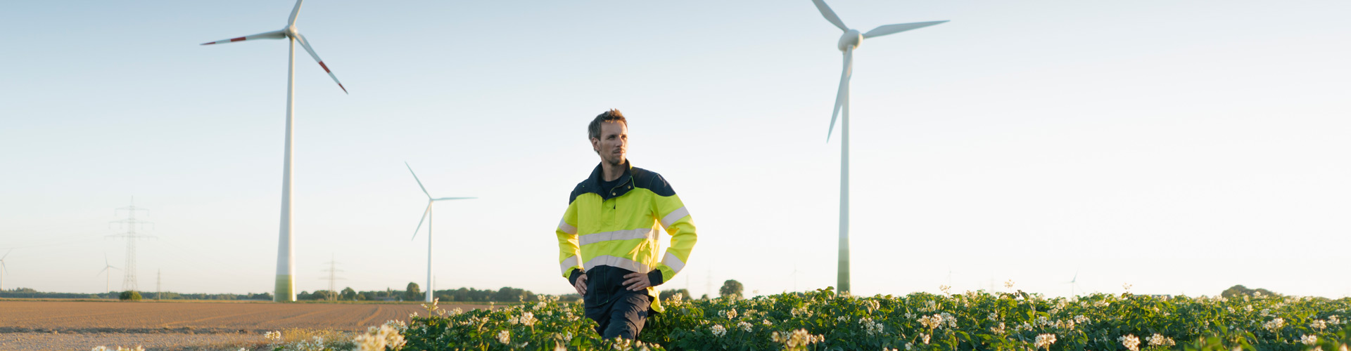 Un homme au milieu des champs avec des éoliennes - Investissement responsable